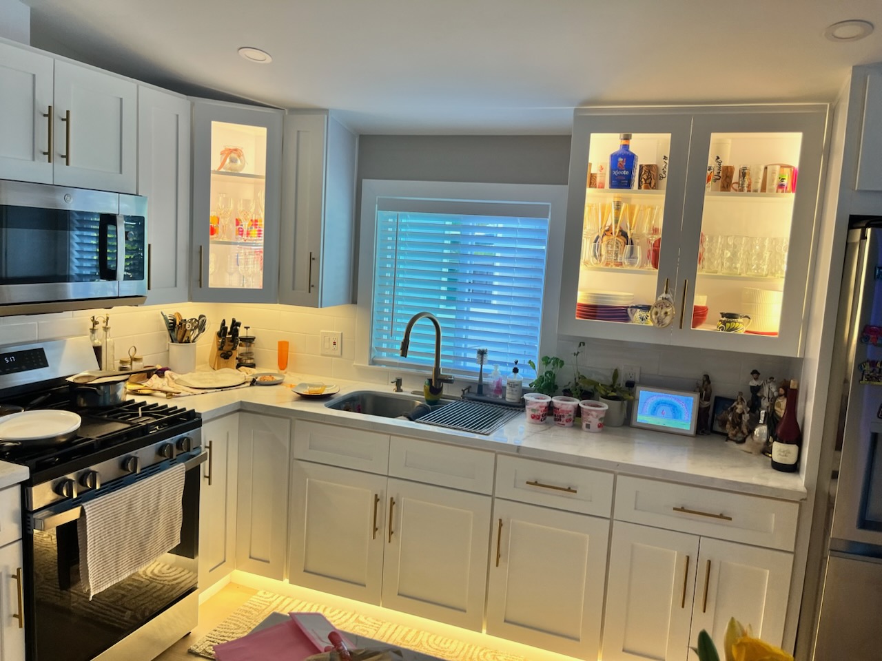 Finished kitchen with lit glass-front cabinets, quartz counters and brass hardware